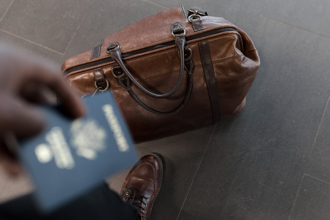 A brown leather duffel bag, representing travel preparedness and the importance of having all essential documents, including an emergency passport.